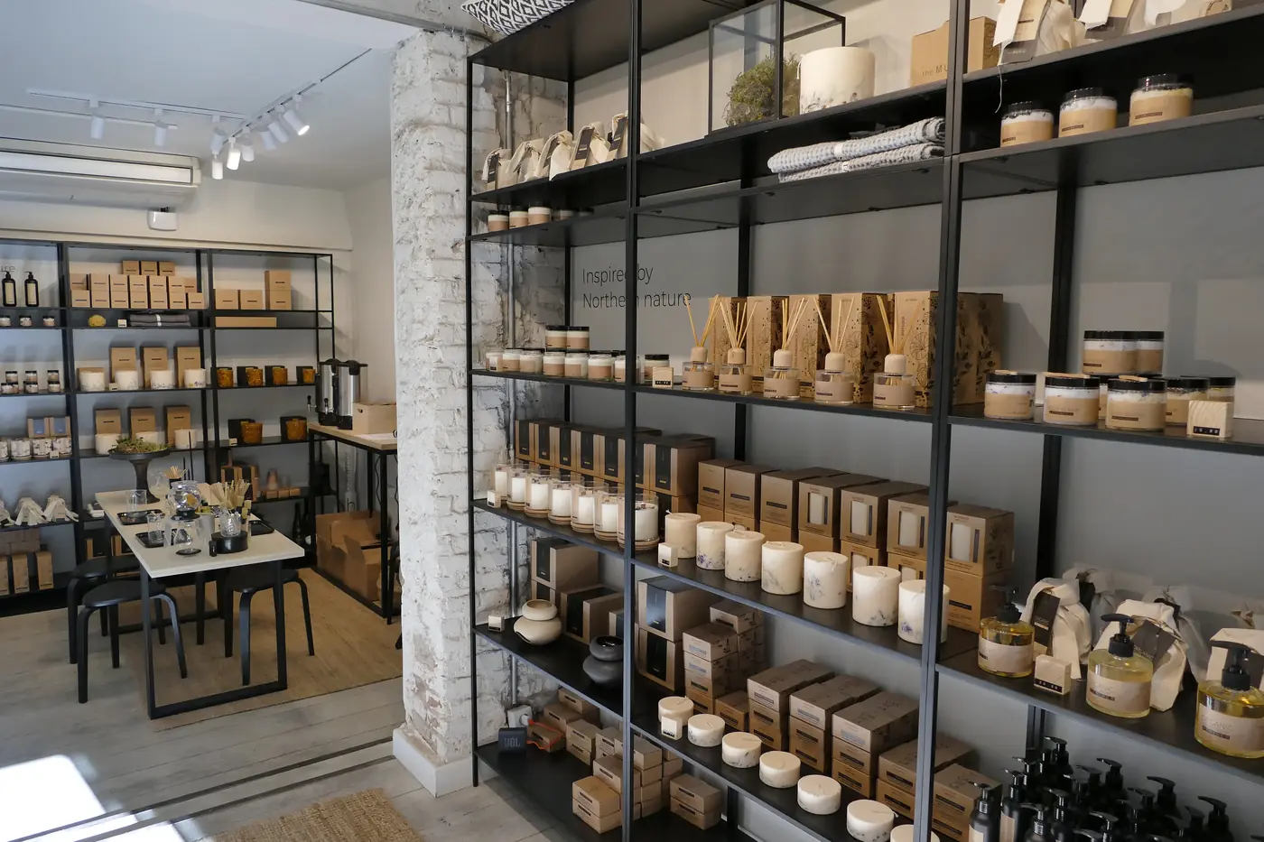Estanterías metálicas con velas, frascos y cajas de cartón.
