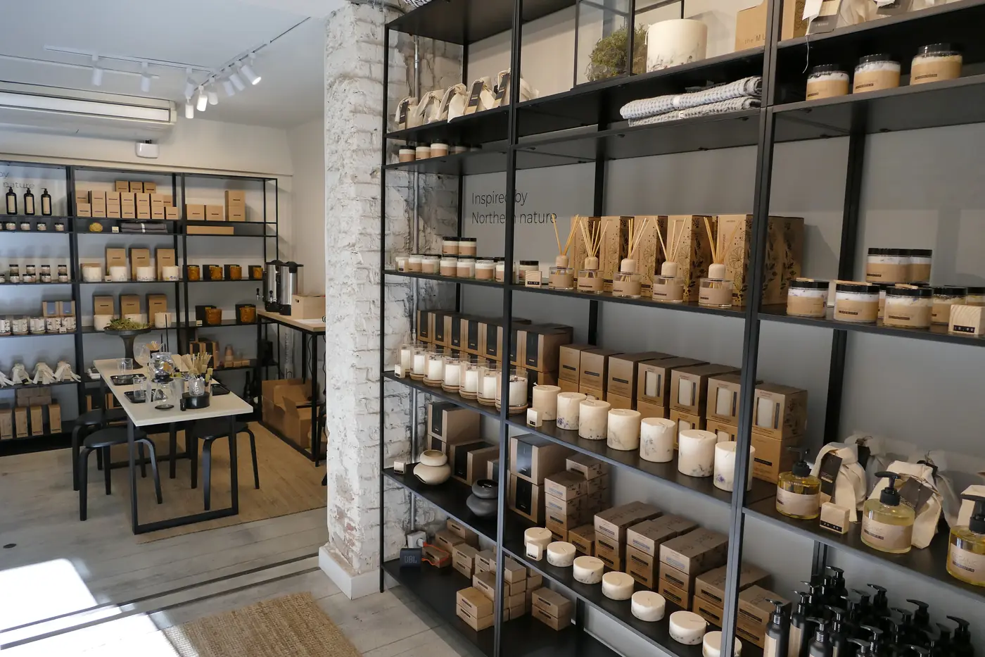 Sala de la boutique con estanterías de producto de suelo a techo y mesa expositora al fondo.