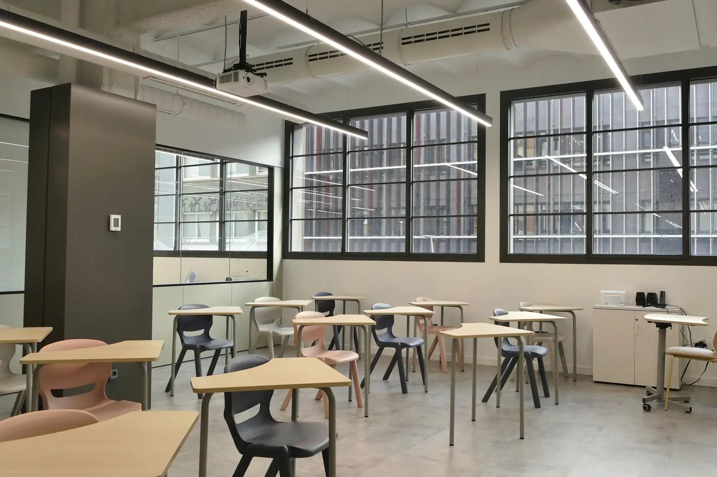Aula del centro educativo con pupitres alineados frente a los ventanales.
