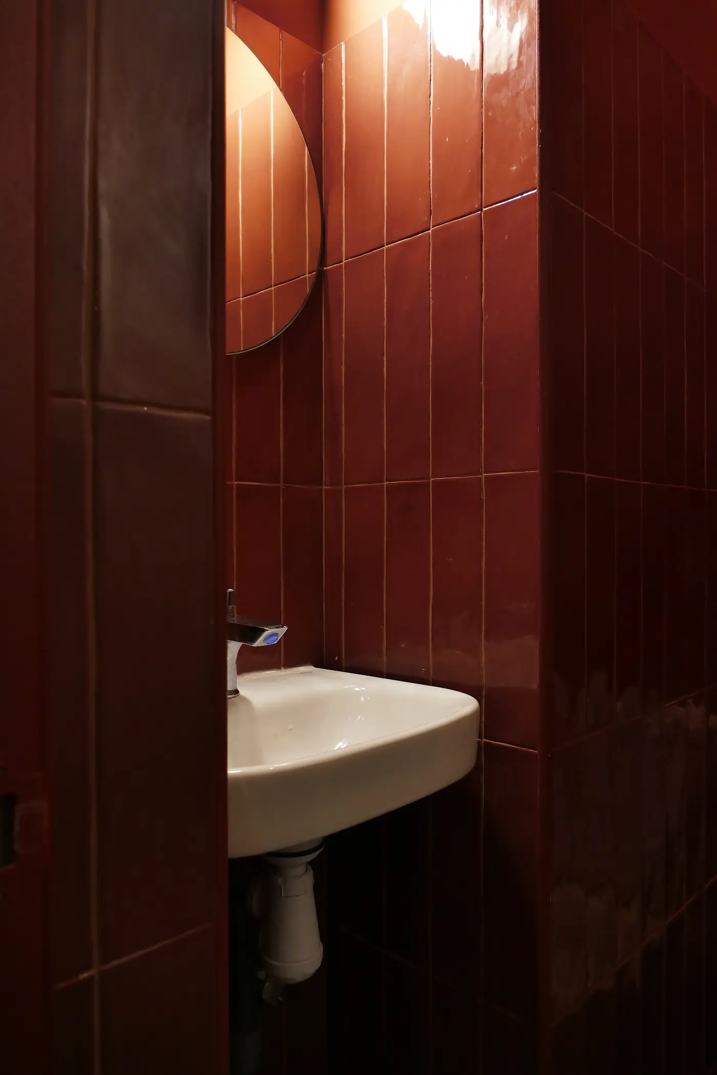 Aseo del local alicatado en rojo, con lavabo de porcelana.