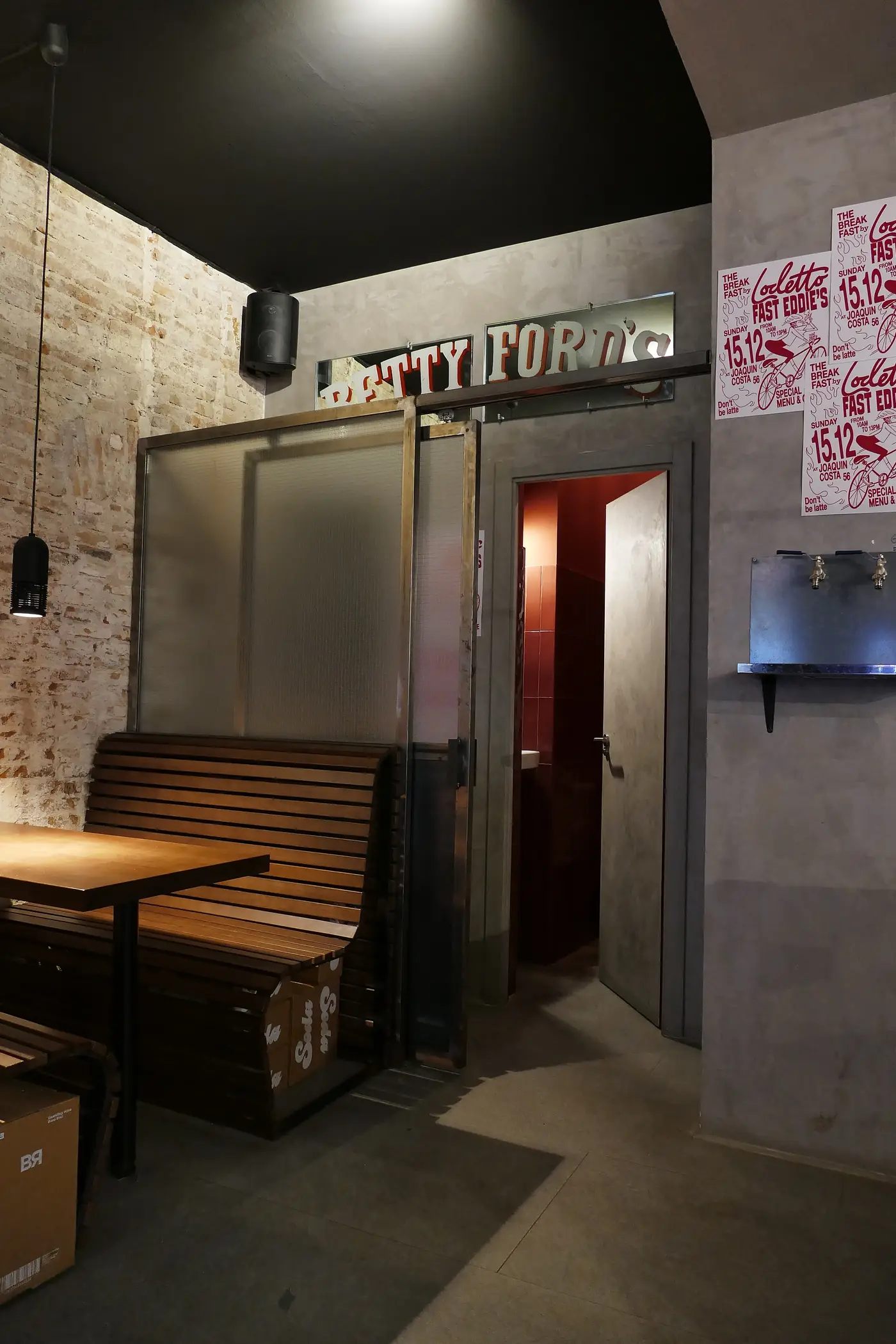 Acceso interior del local, con paso a cocina y muro de hormigón.