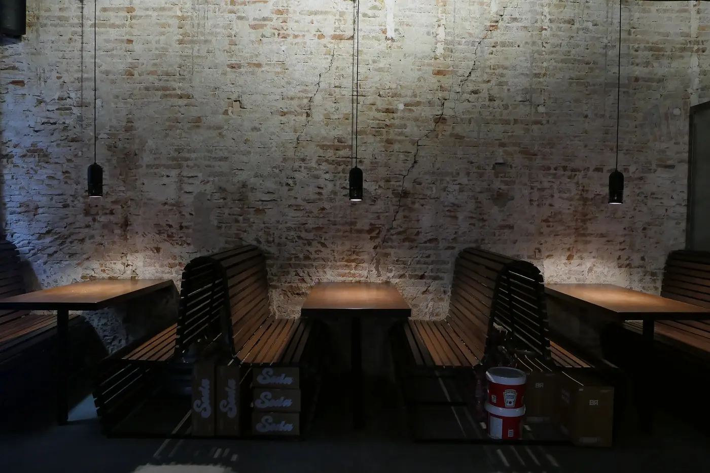 Comedor de la hamburguesería con mesas corridas bajo lámparas colgantes.